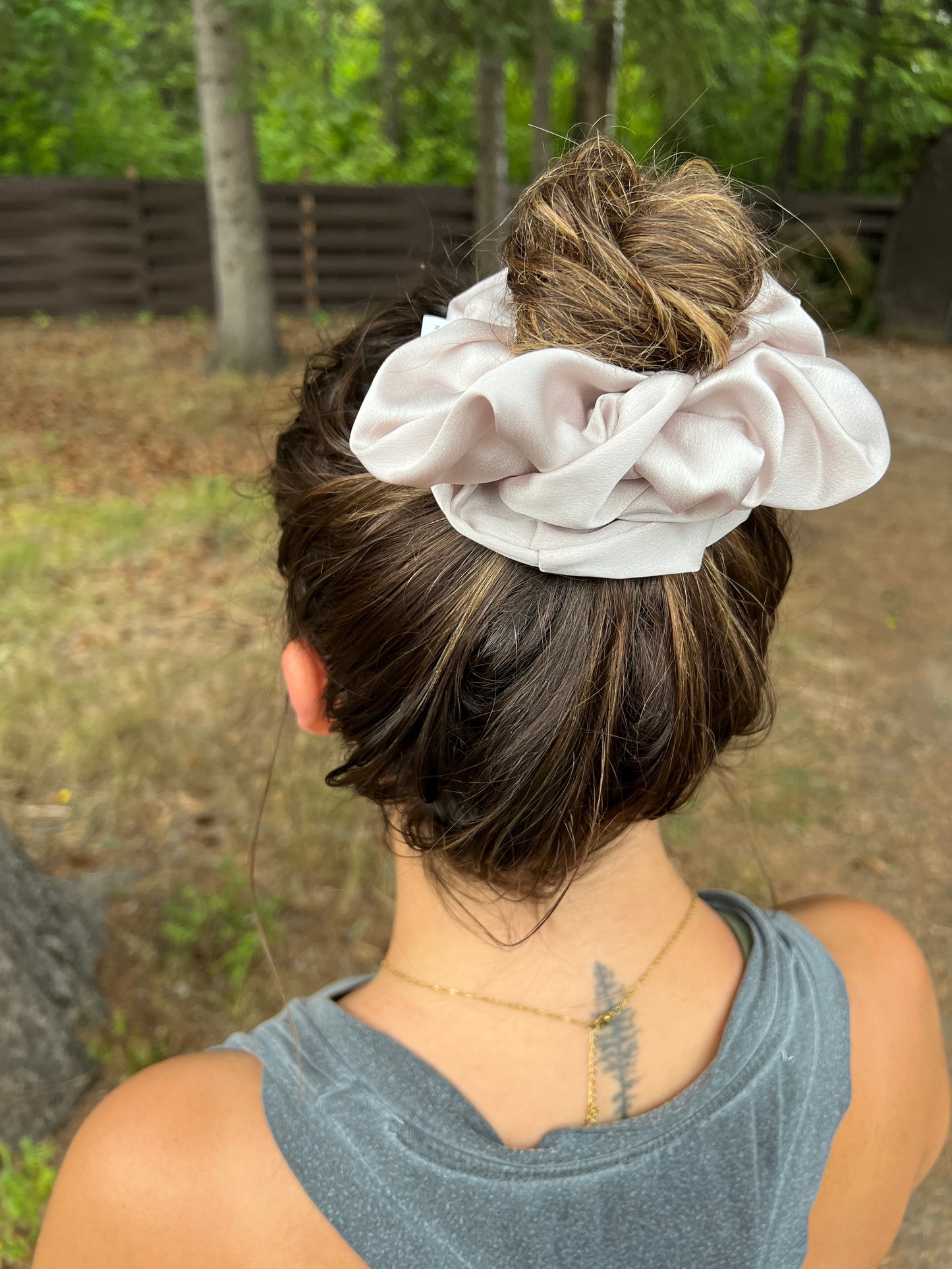 A woman with brown hair wearing a nude coloured scrunchie in her hair.